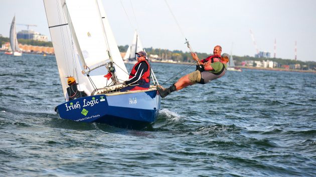 Two men hang onto the side of the Yachting World Diamond twin trapeze boat, steering it.