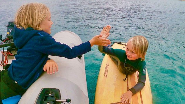 Surfing brothers share a high five.