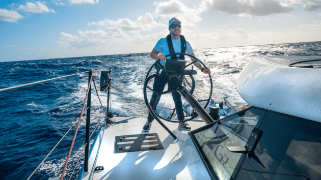 Person at the helm with the sun behind